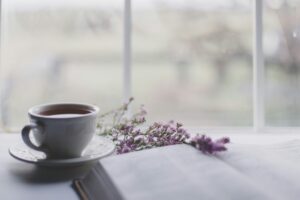 Tasse Kräutertee mit Lavendel auf einem Buch am Fenster – Ruhe und Wohlbefinden für Darm und Seele
