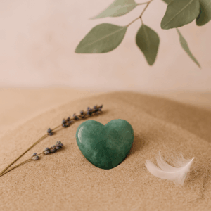 Herzförniger grüner Edelstein auf Sand – Symbol für natürliche Kraft, Vertrauen und Klarheit